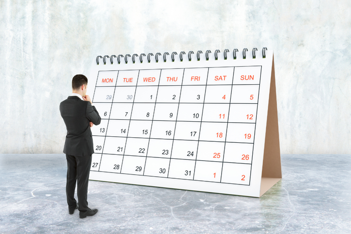 Man standing in front of a large calendar symbolizing anxiety and Sunday Scaries before the work week