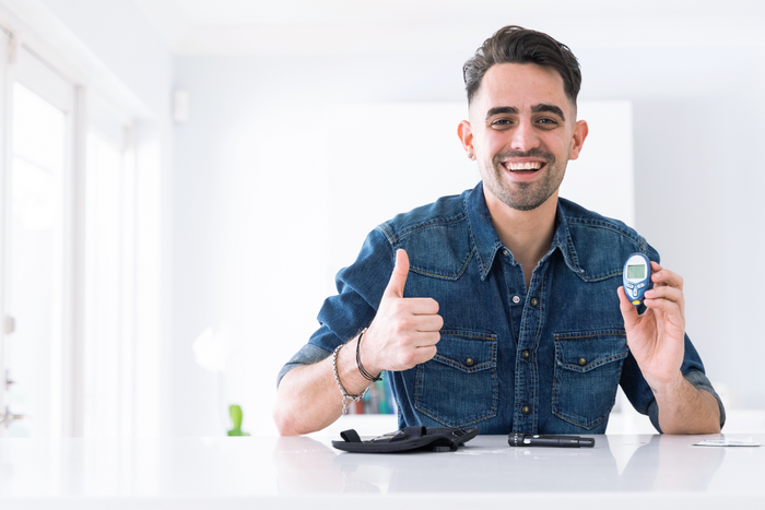 Man smiling with glucose meter highlighting anxiety and blood sugar levels connection