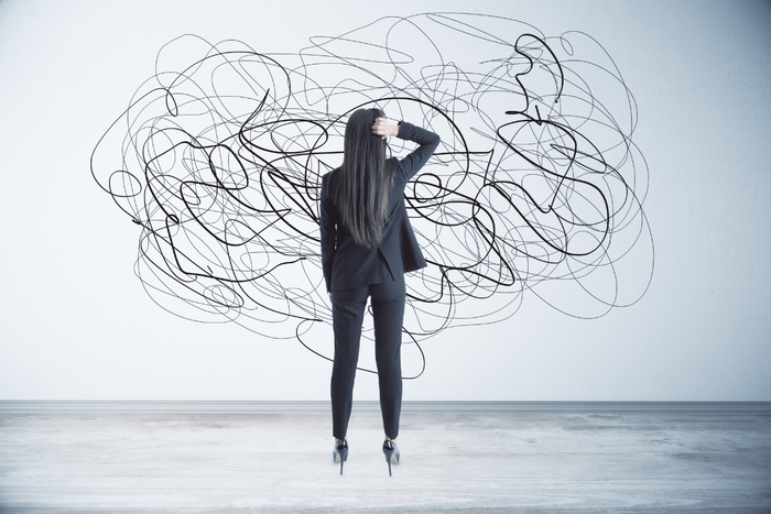 Woman in business attire standing in front of chaotic scribbles, representing a cluttered and overwhelmed mind during stress.
