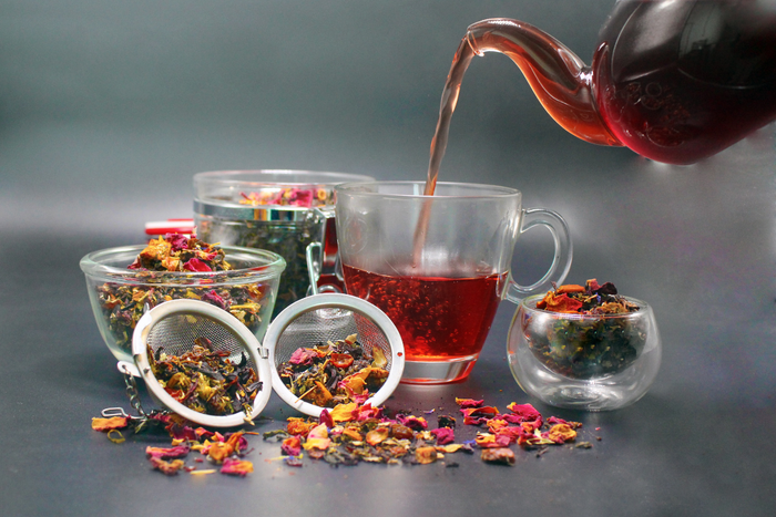 Glass cup of herbal tea with rose petals and loose leaf blend for relaxation