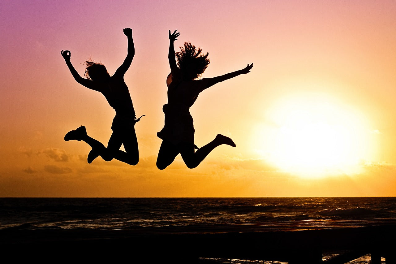 People jumping in front of an ocean sunset