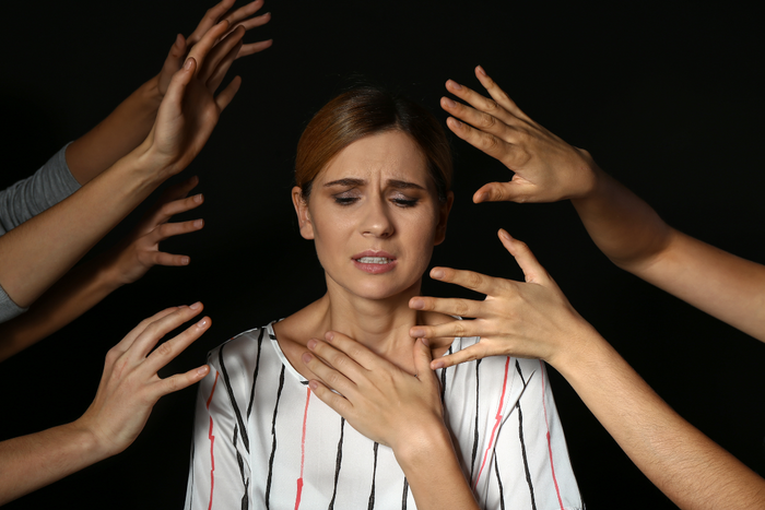 Anxious woman feeling overwhelmed by attention, showing symptoms of social anxiety disorder