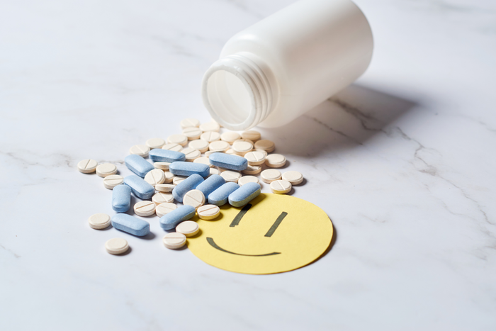 Prescription-style pills beside a smiley face note, symbolizing the phrase happy pills and mood-related medications.