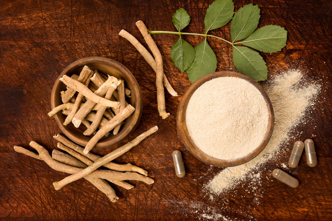 Ashwagandha for stress shown as root, powder, and capsules on wooden table.