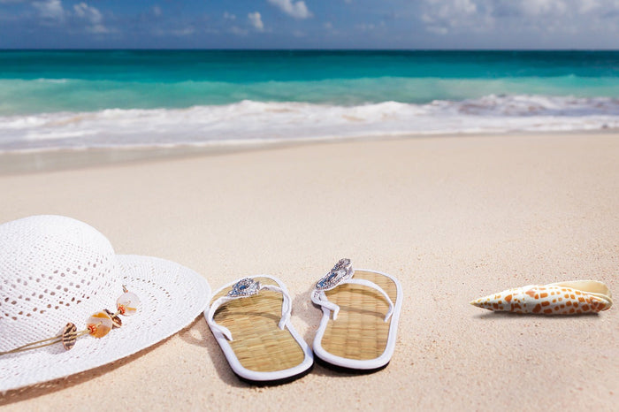 Sandals, hat, and shell lying on the beach