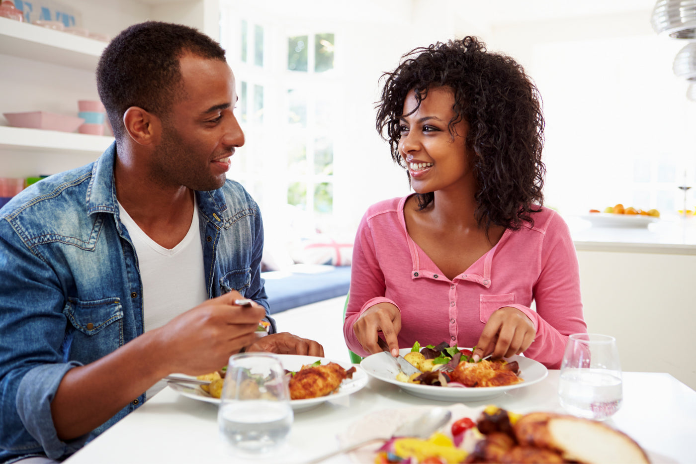 A couple eating a nutritious meal with glasses of water beside them.