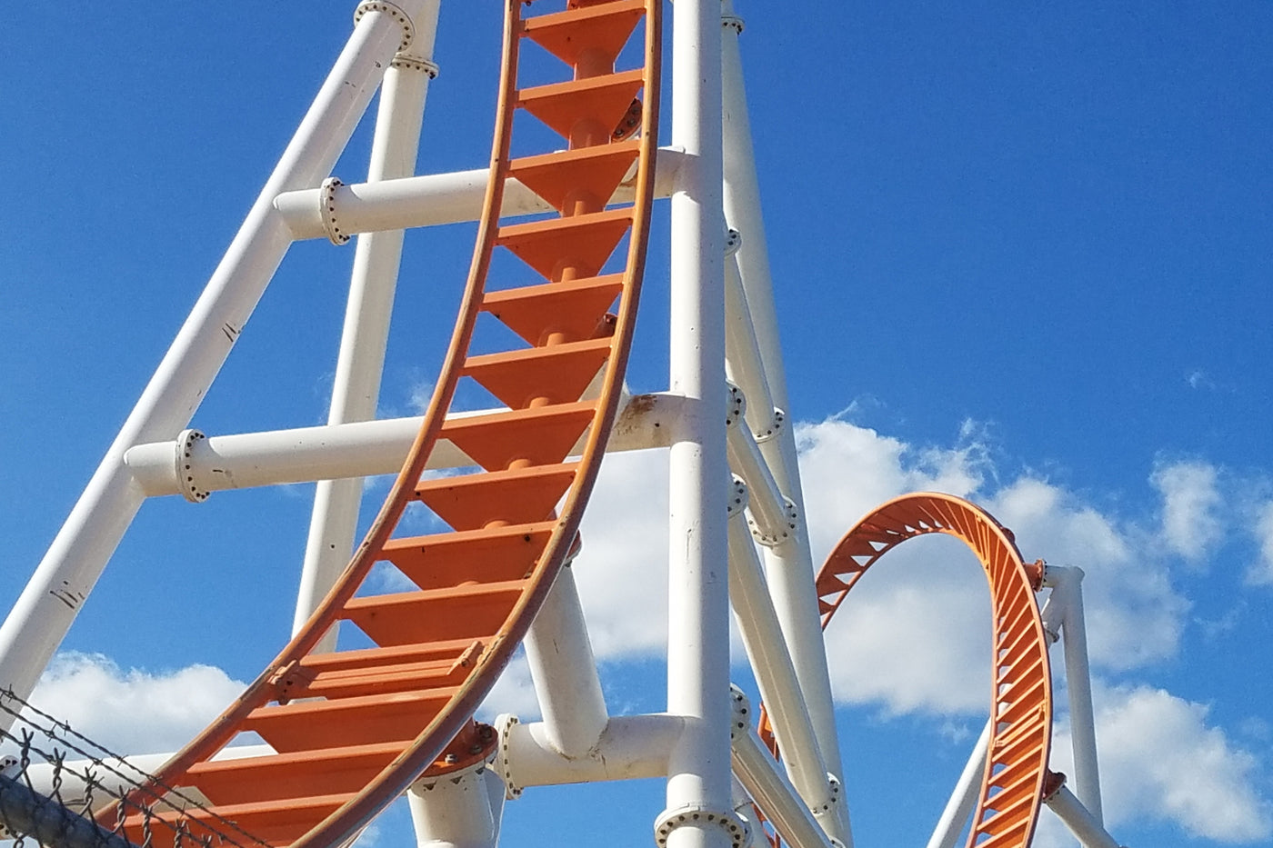 Orange roller coaster track looping against a bright blue sky, illustrating the unpredictable highs and lows of an emotional rollercoaster.