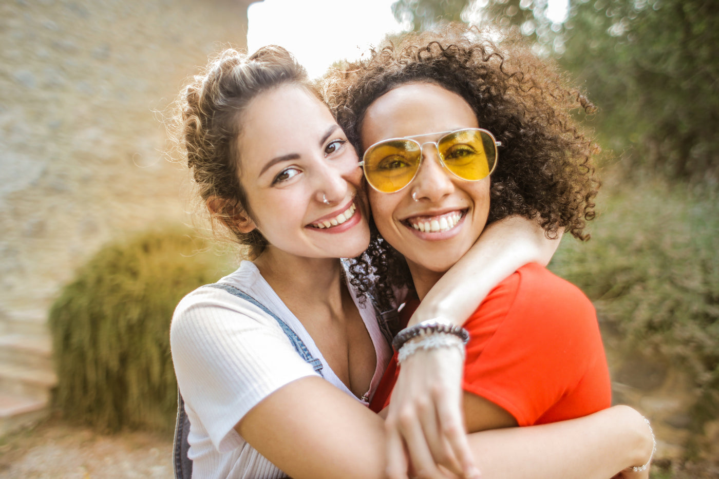 Two friends smiling at the camera and hugging each other.