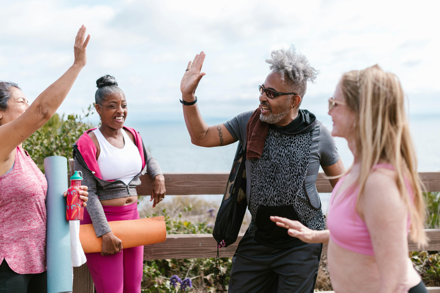Four friends, two women and two men, are high-fiving after an outdoor workout.