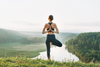 A person doing yoga outdoors at sunrise.