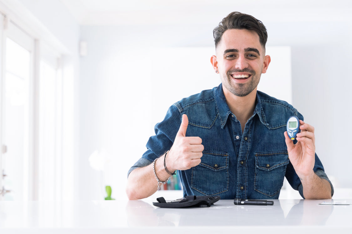 Man smiling with glucose meter highlighting anxiety and blood sugar levels connection