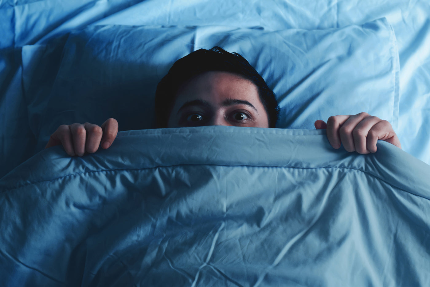 Person hiding under a blanket after a nightmare or vivid dream