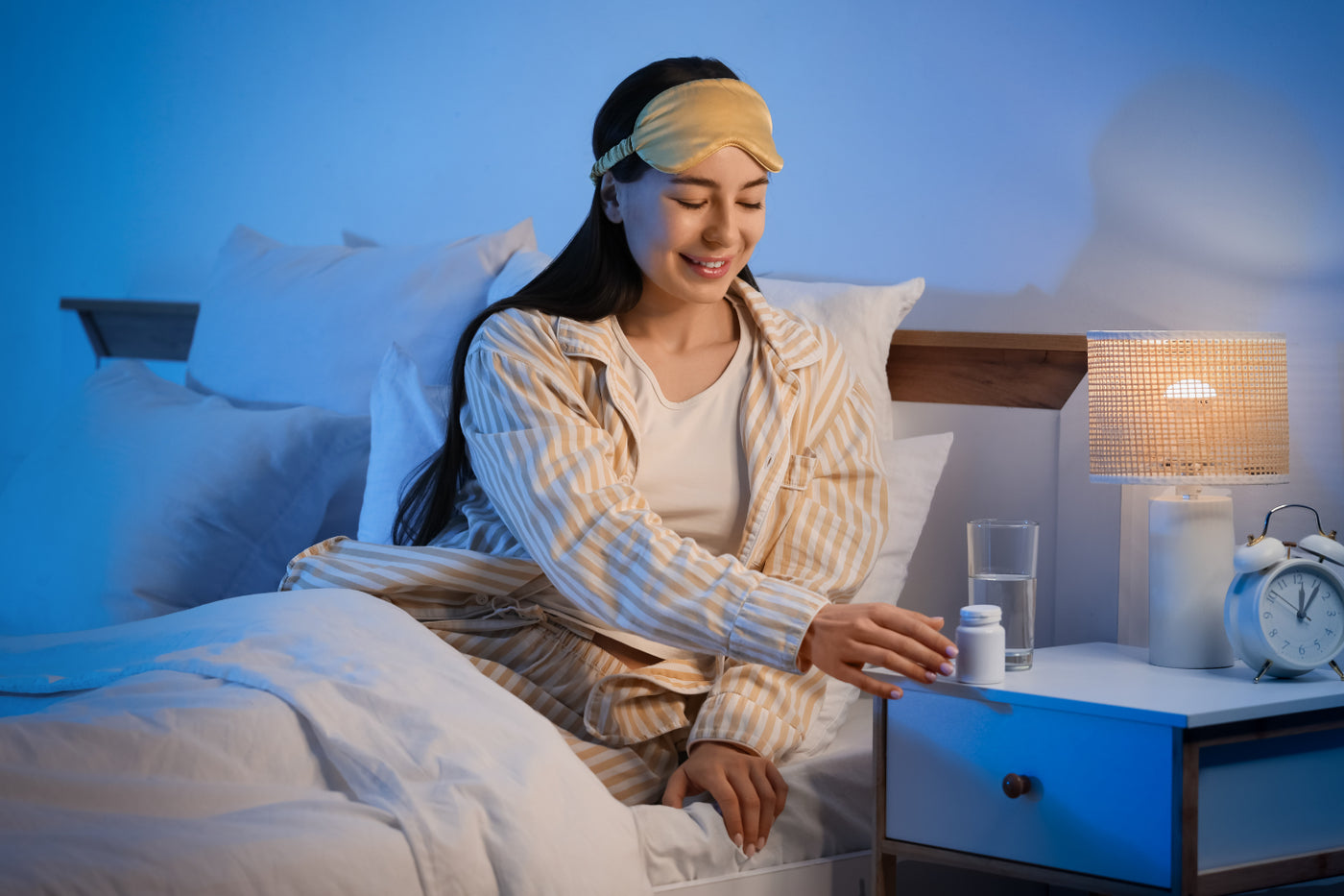 Woman in bed reaching for a melatonin supplement before sleep