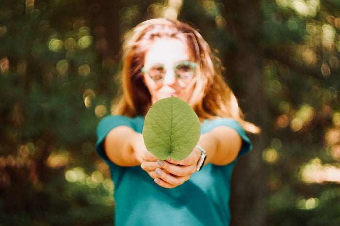 Woman holding a big leaf.