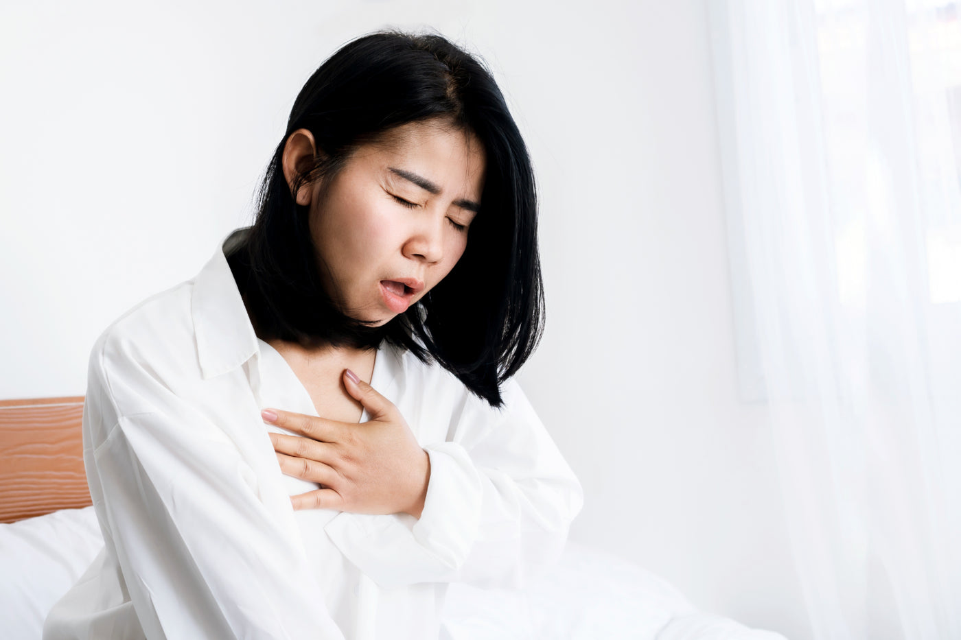 Woman in bed holding her chest during nighttime heart palpitations
