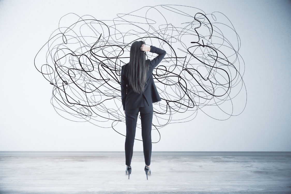 Woman in business attire standing in front of chaotic scribbles, representing a cluttered and overwhelmed mind during stress.