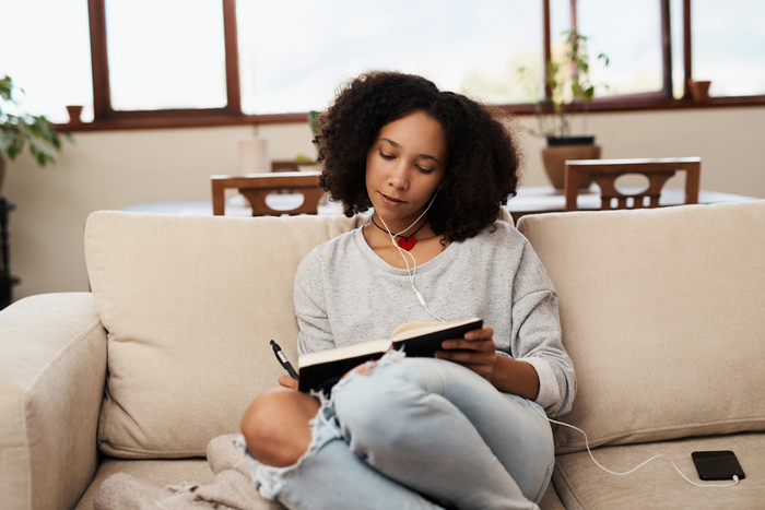 Woman writing in her journal while listening to music.