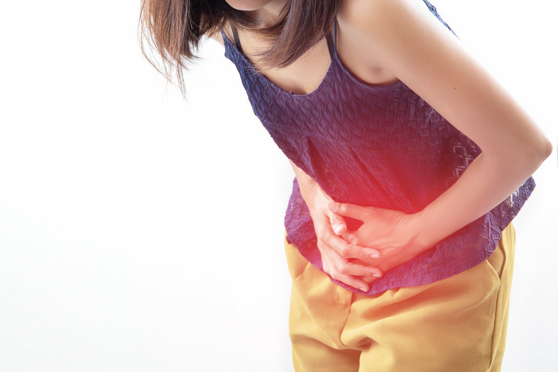 Woman clutching her abdomen in pain, illustrating stress-related digestive issues and gut discomfort.
