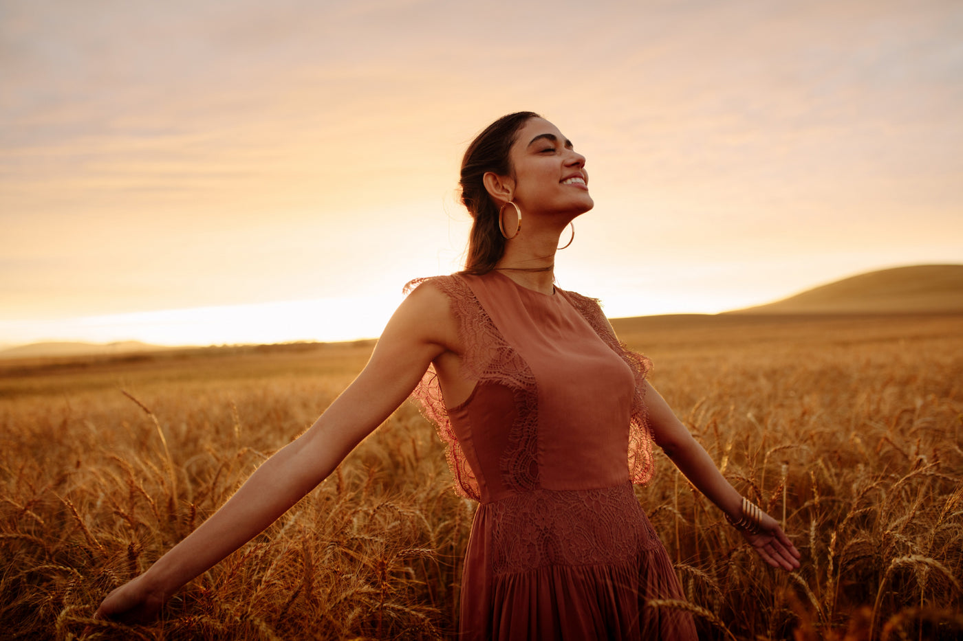 Woman looking happy in a field during sunset.
