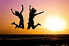 People jumping in front of an ocean sunset