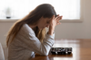 Woman looking forlorn with head on her hands.