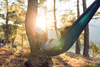 Person reading a book while relaxing in nature.