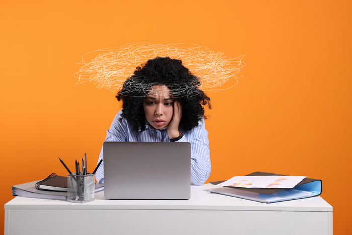 Therapy for burnout illustrated by professional at desk with laptop, charts, and scribble symbol showing stress and overload