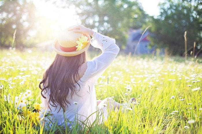 Person sitting in field with sun shining