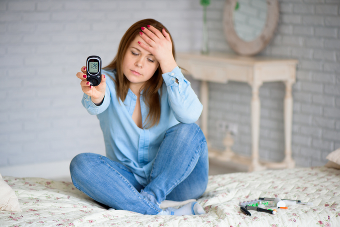Woman checking blood sugar before sleep while feeling tired, showing link between blood sugar and sleep.