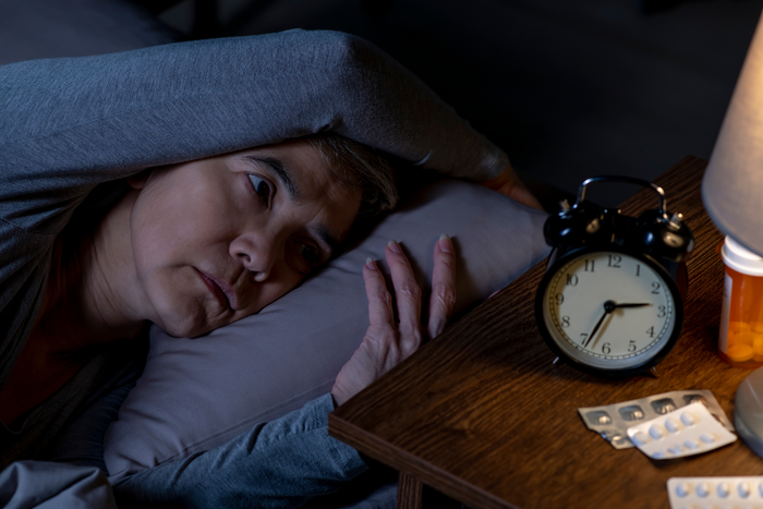 A person in bed wondering how to fall asleep fast.